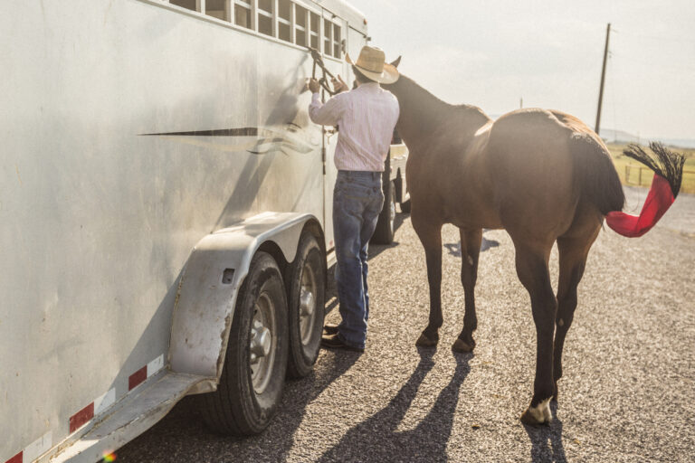 A man tying a rope for his horse, to a horse trailer