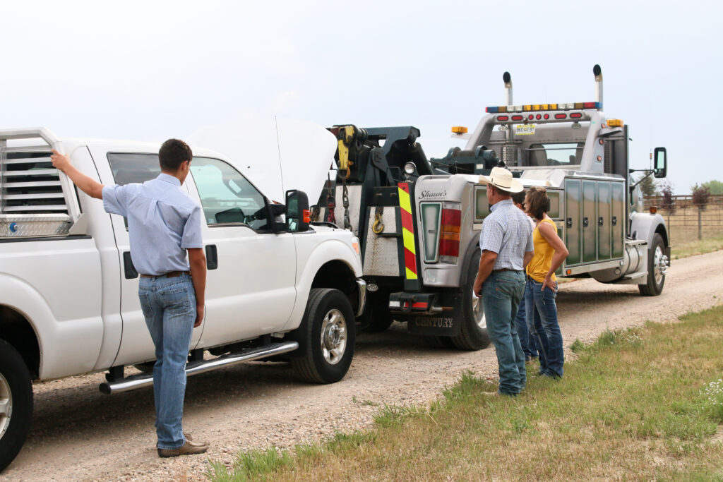 USRider tow truck hauling a pickup truck with people broken down at the side of the road